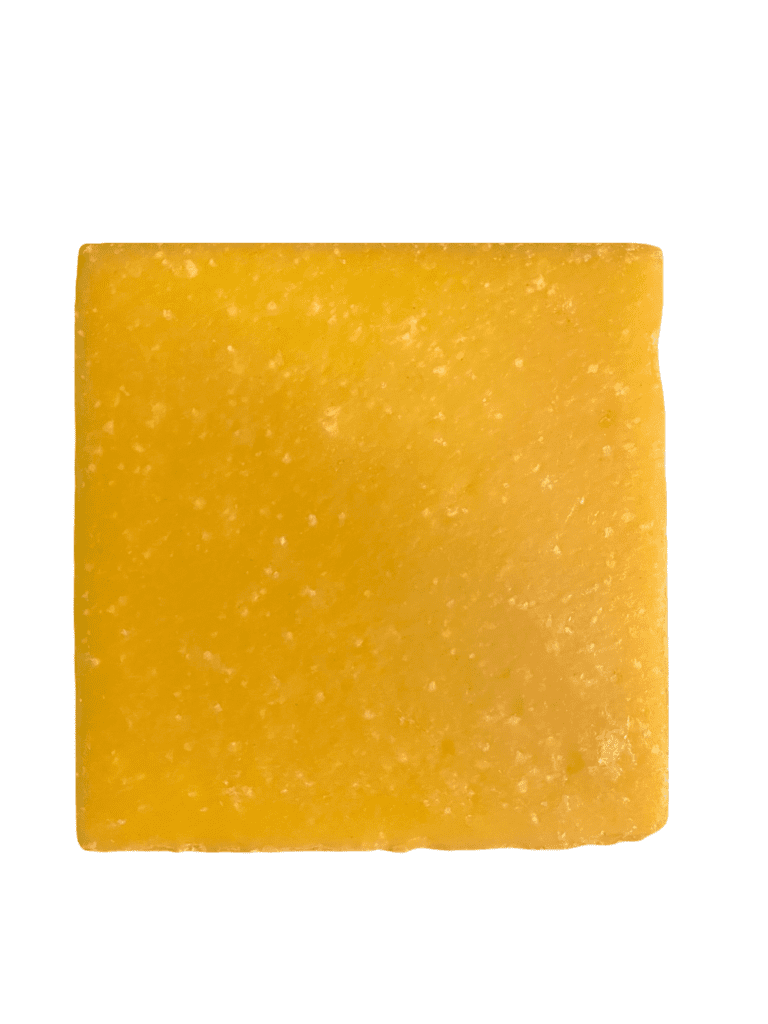 Square piece of yellow cheese on white.